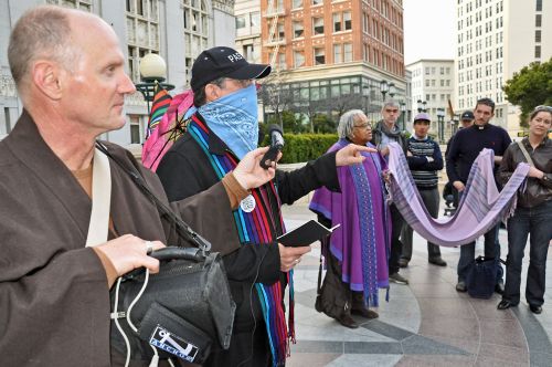 Occupy Interfaith rallies in front of the Oakland City Hall. One pastor wears a mask in solidarity with those banned from the plaza. Credit: Judith Scherr/IPS
