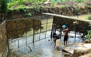 Villagers bathe behind wire mesh to ward off crocodiles in the Nilwala river. Credit: Amantha Perera/IPS