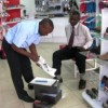 A shop assistant at a Bata store in Kampala assists a customer. Bata is relocating its factory to Kenya. Credit:  Wambi Michael/IPS