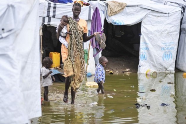 A mother and children walk amongst flooded shelters at the Tomping IDP camp. Credit: UN Photo/Isaac Billy