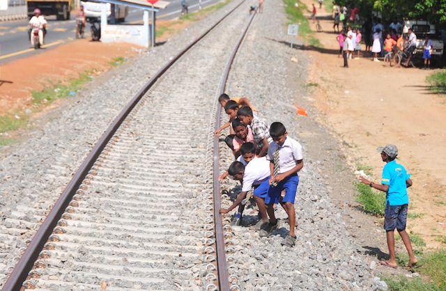 Playful children run to the train track in the village of Kodikaman to collect their coins, which they had placed on the rails to be flattened by passing construction engines. Credit: Amantha Perera/IPS