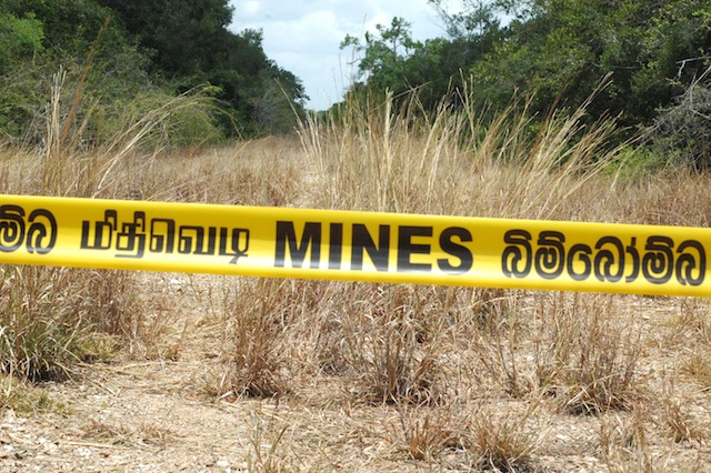Mine warning signs keep visitors off the cleared jungle path where the northern railway once ran, near the village of Murukandhi, in the Kilinochchi District of Sri Lanka’s Northern Province. Credit: Amantha Perera/IPS