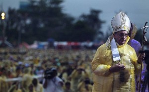 Pope Francis, wearing a yellow raincoat, celebrates mass amidst heavy rains and strong winds near the Tacloban Airport Saturday, January 17, 2015. After the mass, the Pope visited Palo, Leyte to meet with families of typhoon Yolanda victims. The Pope visit to Leyte was shortened due to an ongoing typhoon in the area. Credit: Malacanang Photo Bureau/public domain