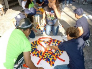 A group of children use bottle caps to create the red ribbon that symbolises the fight against AIDS, in one of the awareness-raising activities carried out in Latin America. Credit: UNAIDS Latin America