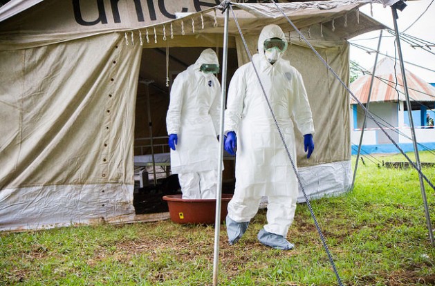 Two health care workers clean their feet in a bucket of water containing bleach after they leave an Ebola isolation facility during an Ebola simulation at Biankouma Hospital in Côte d’Ivoire. Credit: Marc-André Boisvert/IPS