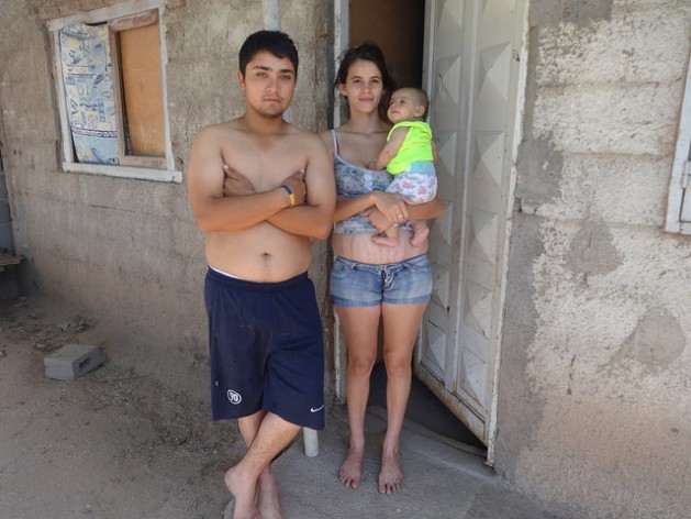 A couple outside their home in a poor neighbourhood in the town of Malvinas Argentinas in the central province of Córdoba. The three members of the family are among the beneficiaries of Argentina’s social programmes. Credit: Fabiana Frayssinet/IPS