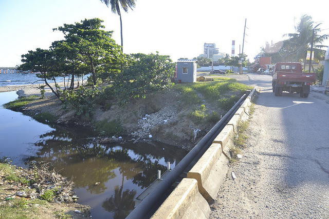 The mouth of the Ñagá River, whose waters have darkened as a result of industrial waste and which has become more narrow due to the loss of the mangroves lining the banks, in the Dominican Republic coastal city of Bajos de Haina. Credit: Dionny Matos/IPS