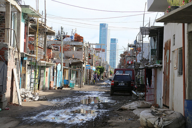 A muddy unpaved street in Villa 31, a shantytown in the heart of Buenos Aires that is home to some 60,000 people. In the background are seen buildings in one of the poshest districts of the capital, just 200 metres away. Credit: Fabiana Frayssinet/IPS