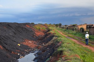 The Masakane village in Mpumalanga sits mere meters away from coal heaps feeding Duvha Power Station. The formal coal industry has failed to bring economic opportunities to local communities, so many residents turn to informal coal mining for an income. Credit: Mark Olalde/IPS