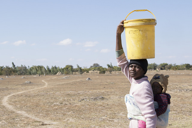 Charity Ncube, 30, of the rural town of Masvingo in southeastern Zimbabwe, carries her child and a 20-litre container of water. Credit: Sally Nyakanyanga/IPS