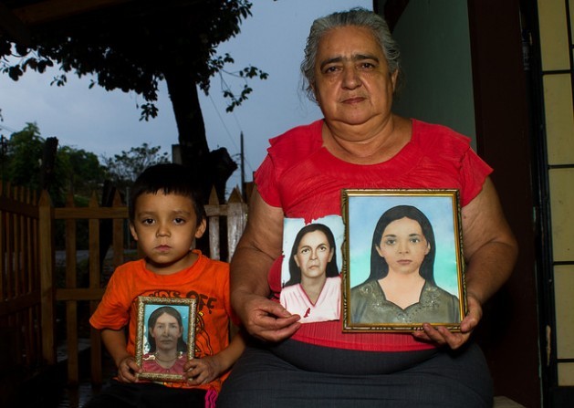 Sofia Romero Pineda, 55, and her grandson hold the few portraits she preserves of some of her family members killed during the military operation which slaughtered some 1,000 inhabitants of El Mozote and neighboring villages in eastern El Salvador. The portraits are of Simeona Vigil, her grandmother; Florentina Pereria, her mother; and Maria Nelly Romero, her sister. Credit: Edgardo Ayala/IPS