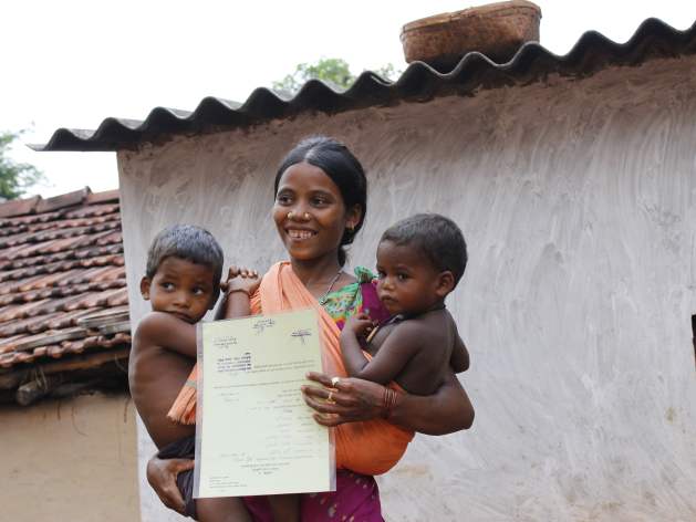 An Indian tribal woman holds up her land tenure document secure in the knowledge that now she can plan long term for her two sons. Credit: Manipadma Jena/IPS