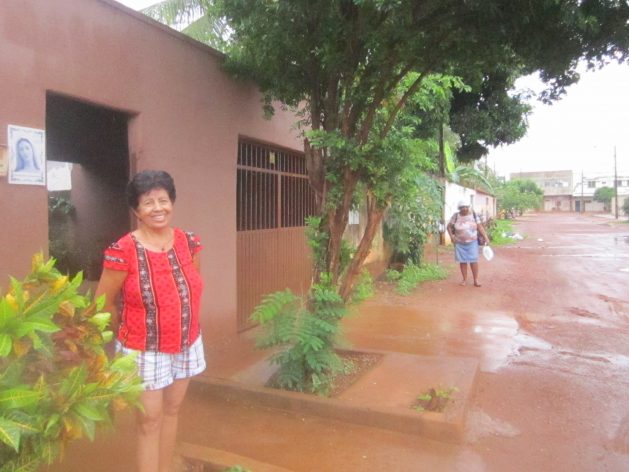 Bernardete Batista de Araujo stands in front of the house where she was relocated in Palmas, together with others displaced by the Lajeado hydroelectric dam in central Brazil. The high walls and a street muddy because of the rain make her miss Vila Canela, her old village on an island that no longer exists on the Tocantins River. Credit: Mario Osava / IPS