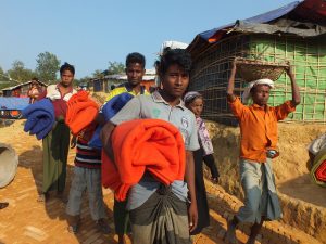Rohingya refugees carry blankets at a camp in Bangladesh. Credit: Naimul Haq/IPS