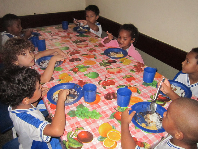 A group of children eat lunch at a school in Itaboraí, 45 km from Rio de Janeiro, Brazil, where thanks to the National School Meals Programme (PNAE) the students in public schools eat vegetables and fresh food from local family farms. Credit: Mario Osava/IPS