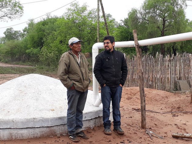 Mariano Barraza (L), a member of the Wichi indigenous people, and Enzo Romero, a technician with the Fundapaz organisation, stand next to the rainwater storage tank built in the indigenous community of Lote 6 to supply the local families during the six-month dry season in this part of the province of Salta, in northern Argentina's Chaco region. Credit: Daniel Gutman/IPS
