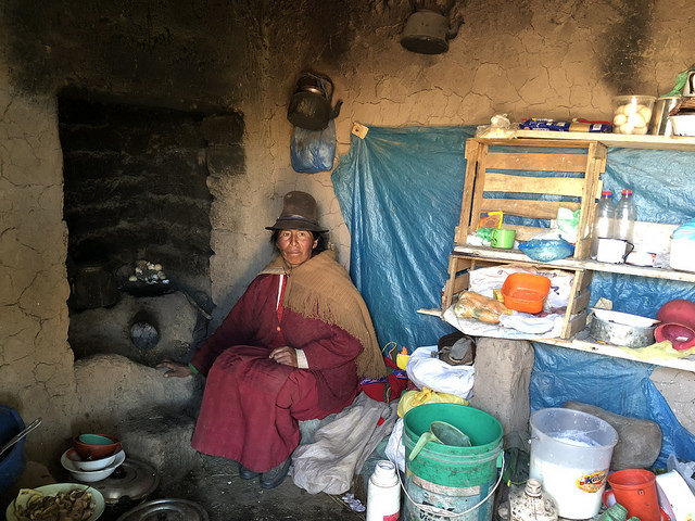 Maruja Anco, 48, sits inside her current home in the Andes highlands village of Quinsalakaya, Peru, where her fireplace lacks a chimney, so the smoke fills the house and affects the family's health. She is one of 30 families about to move into a home that will keep them safe from the cold and smoke. Credit: Annie Solis/IPS