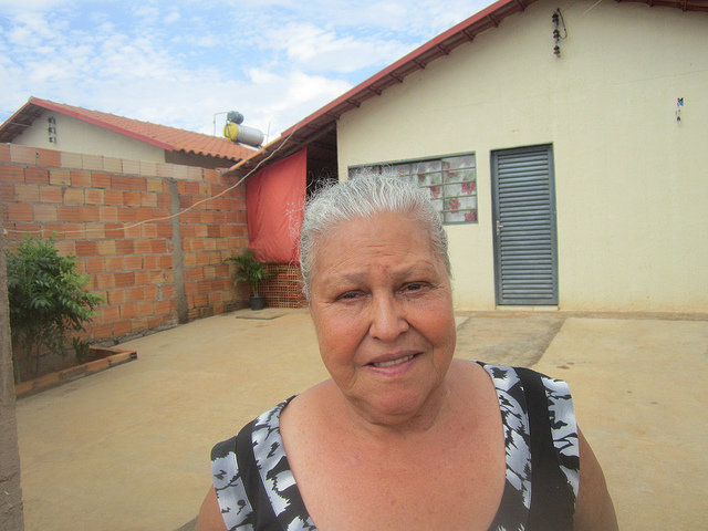 Divina Cardoso dos Santos stands in front of her house in a social housing complex, for which she pays a monthly fee of about 6.5 dollars, on the outskirts of the Brazilian city of Palmeiras de Goiás. That's 24 times less than the rent she used to pay. On the neighbouring rooftop can be seen a solar water heater, which all of the homes in the neighbourhood have. Credit: Mario Osava/IPS