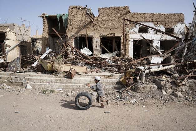 A young boy runs with his tyre past buildings damaged by airstrikes in Saada Old Town; Yemen. Credit: Giles Clarke/OCHA