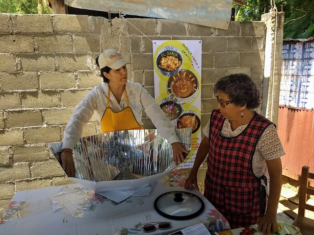 Lorena Harp (L), head of a project that promotes the use of solar cookers in Mexico, shows retired teacher Irma Jiménez how to assemble the device, in the poor neighborhood of Vicente Guerrero, Villa de Zaachila municipality, in the southwestern state of Oaxaca. Credit: Emilio Godoy/IPS
