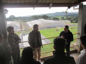 Airton Kunz, head of Research at Embrapa Pigs and Poultry, explains to visitors the Effluent Treatment System of the São Roque Pig Farm, part of which can be seen behind him, in Videira, in the southern state of Santa Catarina, Brazil's largest producer and exporter of pork. Biogas, bioelectricity and biomethane are by-products arising from the need to dispose of pork manure in an environmentally friendly manner. Credit: Mario Osava/IPS