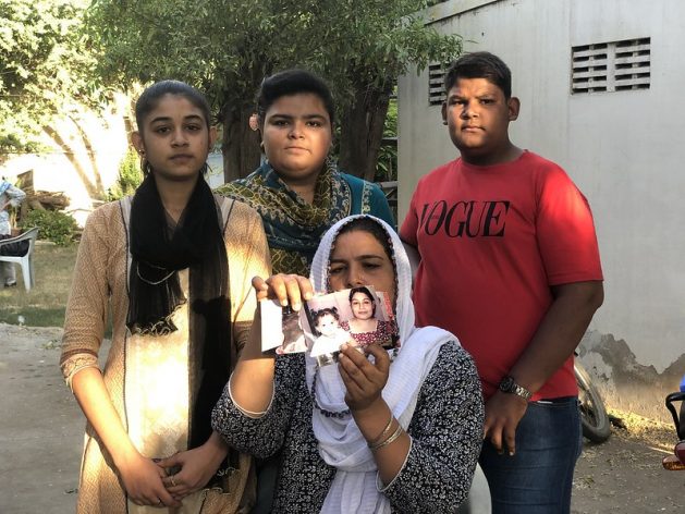 Rita Raja, pictured here with her children, holds up photos of her 13-year-old who had allegedly been abducted and forced to covert her religion and marry her 44-year-old Muslim neighbour. Credit: Zofeen T. Ebrahim/IPS