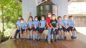 Angélica María Posada, teacher and principal of the school in the village of El Guarumal, in the municipality of Sensembra, in the department of Morazán, in eastern El Salvador, poses with some of her primary school students in front of the tank that supplies drinking water to the school and also to 150 families in this and other neighboring villages. Rainwater is collected on the tin roof and channeled into an underground tank. It is then pumped to a station where it is filtered and purified, before flowing into the tank, ready for consumption. Credit Edgardo Ayala