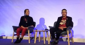At an event in the so-called Green Zone, Canadian native leaders and the non-governmental Indigenous Clean Energy launched a global hub of social enterprises to pass on knowledge and advice during the Glasgow climate summit. In the picture, Mihskakwan James Harper (R) of the Cree indigenous community explains a mixed battery energy storage project built by a private firm and an indigenous company in the province of Ontario, Canada. CREDIT: Emilio Godoy/IPS