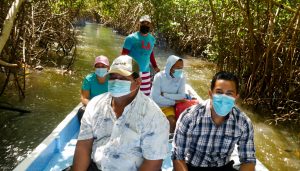 Members of families threatened with eviction ride in a boat down a mangrove channel in the community of Cuatro Vientos, in the municipality of San Luis La Herradura, on the Salvadoran coast. They denounced to IPS that one of the country's main banks now claims to be the owner of the land where they have lived for 20 years. CREDIT: Edgardo Ayala/IPS
