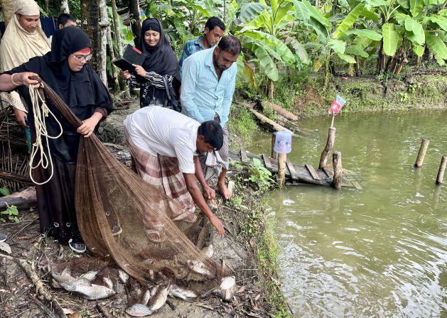 Mosammat Mahmuda catches fish with a net from her pond where she raises different kinds of fishes for commercial purposes in Badarkhali, Barguna district, southern Bangladesh, in September 2022. Credit: Farid Ahmed/IPS