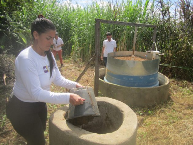 Lucineide Cordeiro loads manure from her two oxen and two calves into the "sertanejo" biodigester that produces biogas for cooking and biofertilizer for her varied crops on the one-hectare agroecological farm she manages on her own in the rural municipality of Afogados da Ingazeira, in the semiarid ecoregion of northeastern Brazil. CREDIT: Mario Osava / IPS