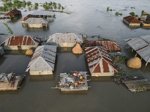 A family shelter on the roof of their small house surrounded by floodwater in Jatrapur Union in Kurigram District, Bangladesh. Credit: Muhammad Amdad Hossain/Climate Visuals