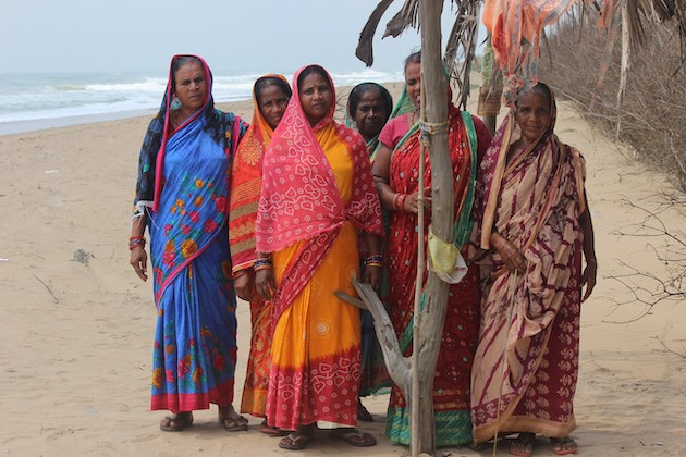 Women’s group poses on the narrow strip of beach that’s all that’s left between the village boundary and the advancing sea. Credit: Manipadma Jena/IPS