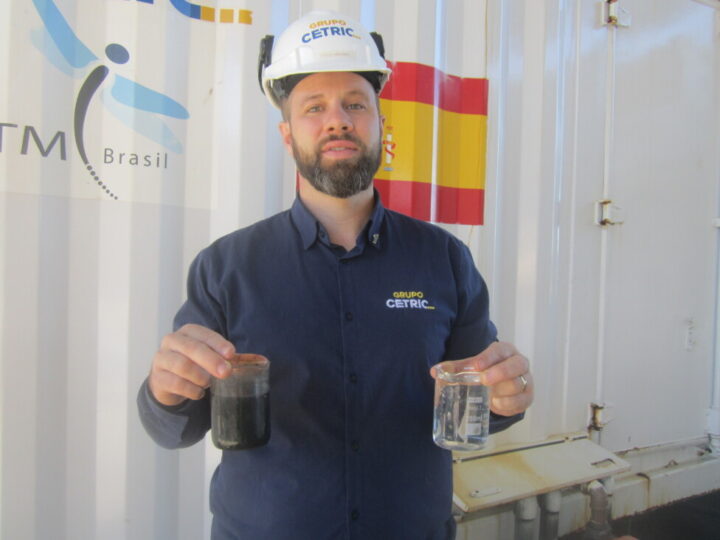 Diego Molinet, a chemical engineer at Cetric, holds in his hands the result of the treatment of effluents from the industrial waste treatment process, with production of biogas and biomethane: a glass with clean water for non-potable reuse and another glass with solid material that can be converted into fertilizer after composting. CREDIT: Mario Osava / IPS