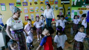 Elena López (left), one of two teachers who teach Náhuat to children in Nahuizalco, in western El Salvador, leads one of the morning's learning practices, in which the children, walking in circles, sing songs in the language of their ancestors, the Pipil people. CREDIT: Edgardo Ayala / IPS