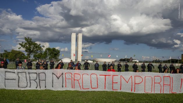 Indigenous people gathered in Brasilia during the Free Land Camp, which is held every April in the capital, demonstrate against the time frame law, with the National Congress building in the background. Credit: Gustavo Bezerra / IndiBSB