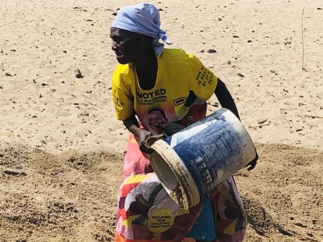 In order to reach the water lying deep underneath, Enia Tambo (59) uses a white 25-liter plastic bucket to pull out huge amounts of sand in the Vhombozi River in Mudzi district located in Zimbabwe’s Mashonaland East Province. Credit: Jeffrey Moyo/IPS.