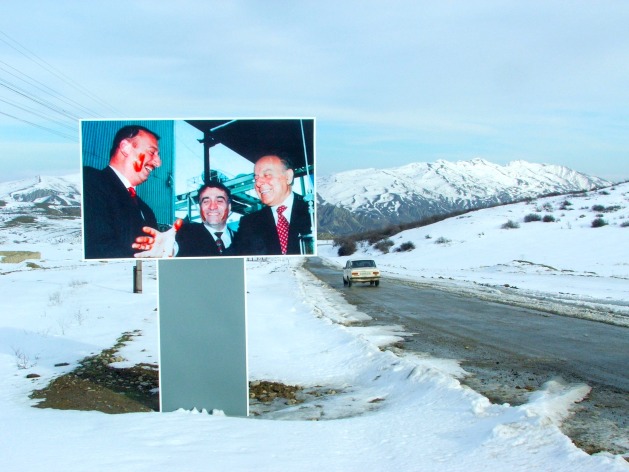 A poster of the Aliyev clan appears stained with red paint next to a secondary road in Azerbaijan. In power for three decades, they hope that the United Nations Climate Summit will help polish their image. Credit: David Fielke / IPS
