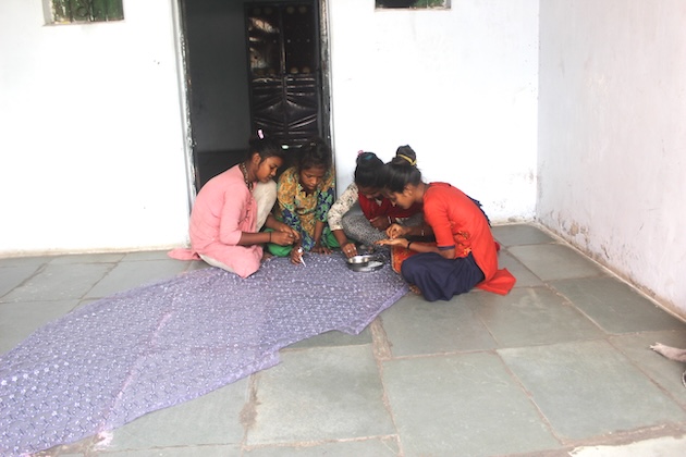 Home-based worker Dipikaben with her teenage friends in Odni Chawl slum, gluing stones and beads on a fabric length in Ahmedabad city in Gujarat. Credit: Manipadma Jena/IPS