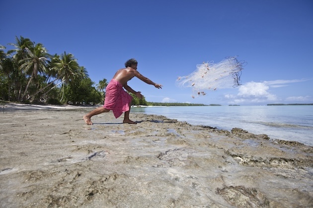 A fisherman on the coast of Funafuti, Tuvalu, throwing a weighted net out into the seawater, a traditional form of fishing. Credit: Rodney Dekker / Climate Visuals