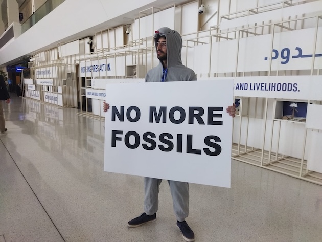 A climate activist holding a placard during COP 28 in Dubai, demanding the end of the use of fossil fuels. Credit: Umar Manzoor Shah/IPS