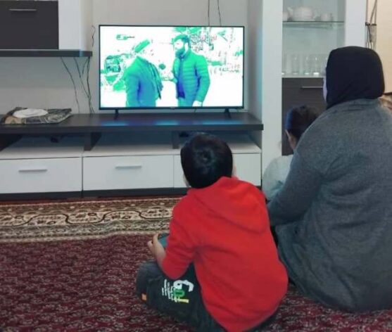 A woman and children watch television at home in Afghanistan, where Afghan female journalists face growing restrictions under Taliban rule. - Afghan media workers face growing restrictions under Taliban rule, with women journalists pushed further from reporting, broadcasting and public visibility. Credit: Learning Together.
