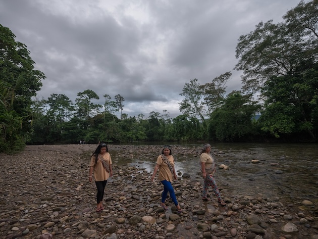 Indigenous women walk along a river in the Amazon rainforest. According to Global Witness, Indigenous peoples and small-scale farmers accounted for nearly three-quarters of the land, and environmental defenders killed globally in 2025. The report highlights the growing risks faced by communities defending their lands, livelihoods and ecosystems from environmental destruction and resource exploitation. Credit: Global Witness