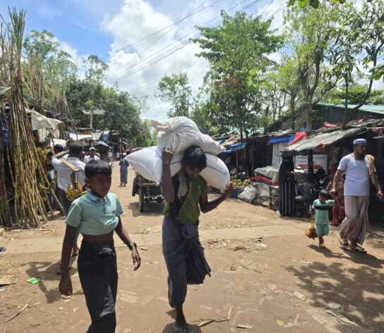 A man carries his family’s food ration from a WFP distribution point to his shelter in Camp 11, Balukhali, Bangladesh, on September 24, 2026. Credit: Mohammed Zonaid/IPS