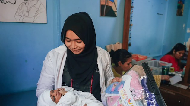 A healthcare worker cradles a newborn baby at a maternal health facility, illustrating frontline efforts to protect mothers and infants amid mounting concerns over the impact of extreme heat on pregnancy, childbirth and newborn health. Credit: Wellcome