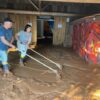 Iyá Patrícia d’Xangô (Mãe Patrícia) and her husband, Ogan Cézar d’Oxalá (Cézar Paulo Fogolari), cleaning their religious site three months after the mudslide in 2024.
