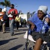 An elderly woman in a wheelchair carries away a bottle of water distributed by UN Brazilian peacekeepers. Credit: UN Photo/Marco Dormino 