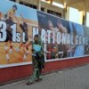 A woman walks by a board advertising the now-postponed National Games at the Qayyum Sport Complex in Peshawar.  Credit: Ashfaq Yusuzfai/IPS