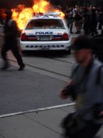 A police car burns at Bay & King Streets in Toronto.  Credit: Marty Olauson/IPS