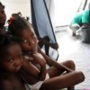 Young girls sit within their three-section tent as their father cleans the floor, at a new camp site in Croix des Bouquets, Haiti. Credit: UN Photo/Sophia Paris